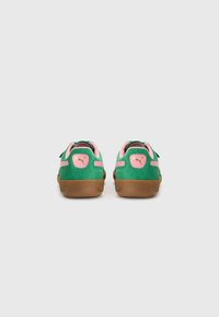 Grønne semskede sneakers med rosa detaljer, som har en gullogo og en brun gummisåle. Designet inkluderer en jevn tekstur og rund form.