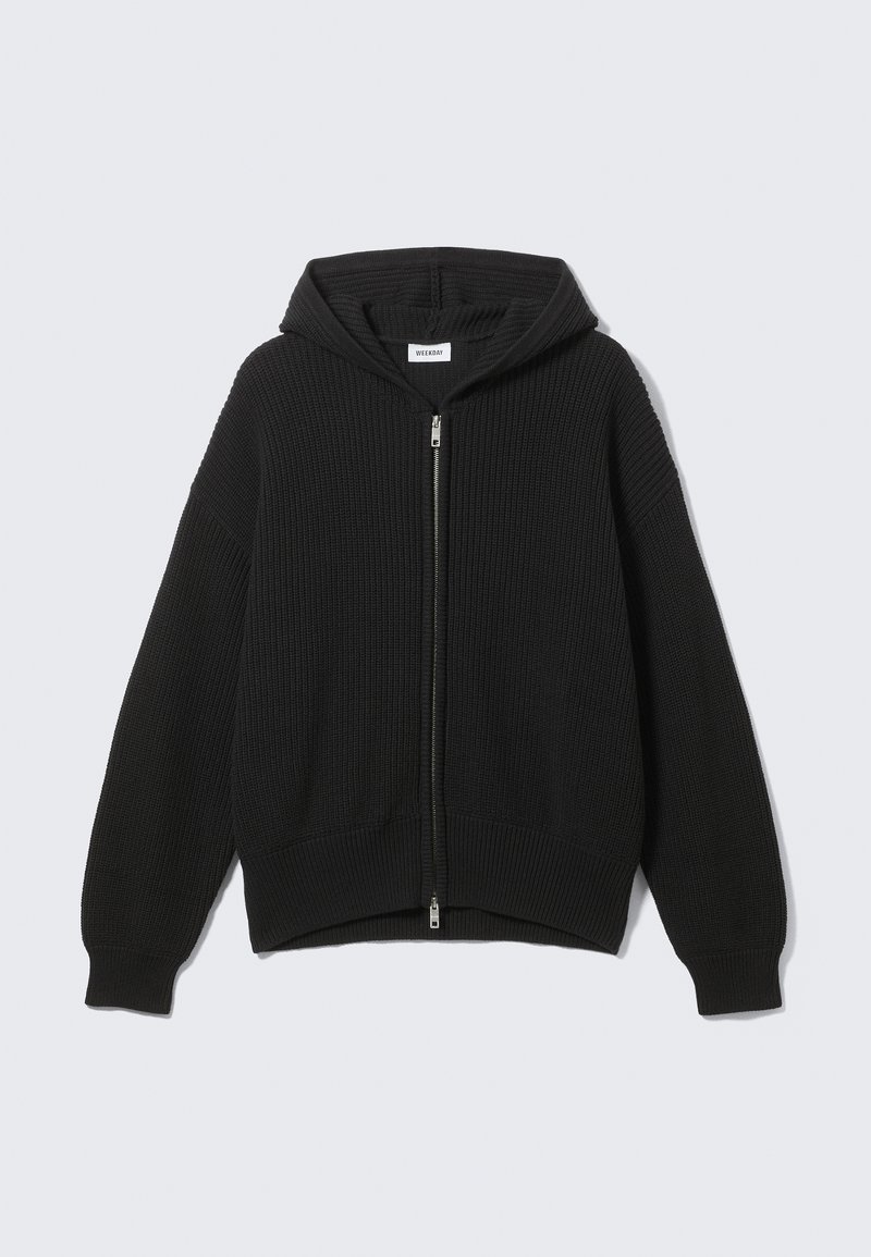 Schwarzer gestrickter Hoodie mit Reißverschluss, geripptem Strukturmuster, weiten Ärmeln und lockerer Passform. Mit silbernem Reißverschluss und weichem Innenfutter.