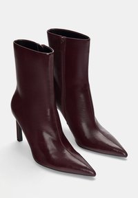 Burgunderfarbene Lederstiefeletten mit spitzer Zehenform, hohen Stiletto-Absätzen und einem seitlichen Reißverschluss für einfaches Anziehen, mit einer glatten, glänzenden Oberfläche.