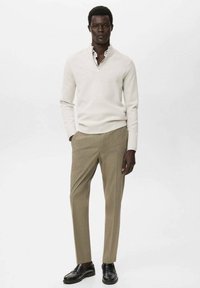 Lichtbeige zip-neck trui, slim-fit khaki broek, en zwarte loafers. Gladde textuur; minimalistisch ontwerp zonder zichtbare patronen.