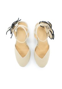 Sandali espadrillas beige con punta affusolata, suola piatta, cinturini incrociati e dettagli floreali in tessuto nero. Fodera interna liscia.