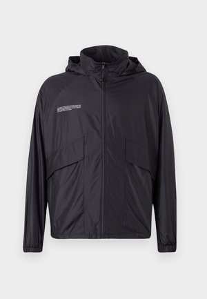 Lightweight black jacket with a zip front, hood, and large side pockets. Made of smooth, water-resistant material, featuring subtle text detail.