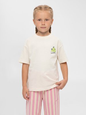 Ung pige med flettet hår iført en hvid t-shirt med et lille pære-motiv og lyserøde og hvide stribede bukser mod en ensfarvet baggrund.