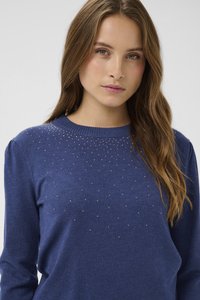 Tumesinine kampsun ümmarguse kaelusega, pikkade varrukatega ja dekoratiivse helmeste kaunistusega, mis on paigutatud üleminekuga muster. Pehme tekstuur.