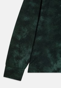 Langærmet, mørkegrøn T-shirt med marmoreret tekstur og manchetter på ærmerne. Blødt stof med en afslappet pasform.