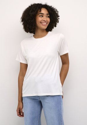 T-shirt blanc à manches courtes en tissu doux, avec un col rond et une coupe décontractée. Associé à un jean en denim bleu clair.