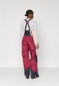 Snehové nohavice s plným pokrytím v burgundskej, námorníckej a ružovej farbe. Majú nastaviteľné popruhy, vodoodpudivú tkaninu a zosilnené manžety pre zvýšenú odolnosť.