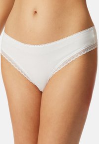 Witte katoenen slips met een golvende kantafwerking langs de tailleband en beenopeningen, met een gladde textuur en een minimalistisch ontwerp.