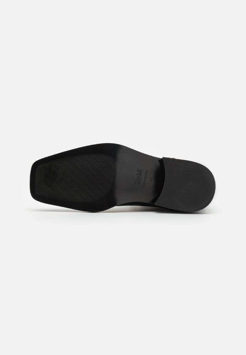 Schwarze Schuhsohle von einem Geschäftsschuh mit einem glatten, flachen Design, das ein strukturiertes Griffmuster und eine leichte Krümmung an der Ferse aufweist.