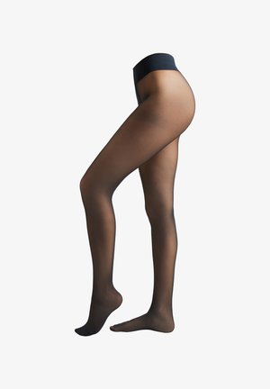 Pravý boční pohled na nohy v průhledných černých silonkách s zesíleným pasem, jedna noha celá na zemi, druhá na špičkách.