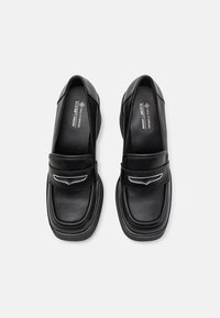 Mocassins noirs en cuir végan avec un bout arrondi, des accents latéraux oversize et une semelle intérieure rembourrée. Talon plat et texture lisse.