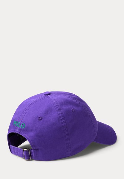 Μωβ βαμβακερό καπέλο μπάσκετ με κυρτή γείσο, με πράσινη κεντητή λέξη "POLO" στο πίσω μέρος και ρυθμιζόμενο κλείσιμο με λουρί.