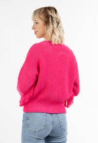 Pullover a maglia di un vivace rosa con frange sulle maniche e orlo a costine. Vestibilità ampia, maniche lunghe, tessuto testurizzato. Stile casual.