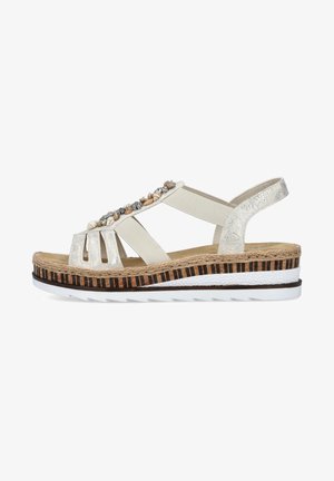 Sandale beige clair avec des accents décoratifs de coquillages, des sangles élastiques et une semelle multi-couches présentant une texture tissée et des rayures noires.