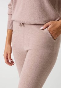 Conjunto de loungewear de color rosa claro de punto, que cuenta con una cinturilla elástica con cordón, puños acanalados y bolsillos laterales para mayor comodidad.
