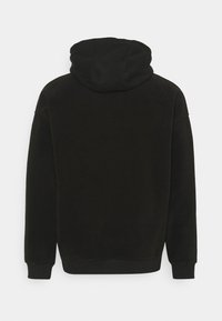 Sort hættetrøje med blød stofstruktur, ribbede manchetter og kant. Viser bagvenden med et sømløst design og minimal detaljer.