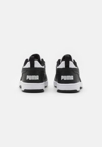Sneaker bianco e nero con tomaia in pelle liscia, suola in gomma, colletto imbottito e grande marchio 'PUMA' bianco sul tallone.