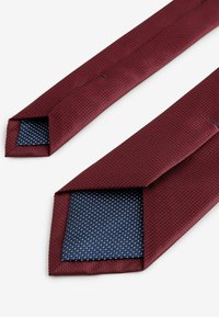 Bordeaux tekstureret slips med en marineblå prikket underside. Har et klassisk spidst design og en detaljeret stofvævning.