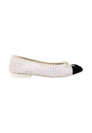 Chaussure plate blanche texturée avec bout arrondi noir, petit nœud blanc et talon bas sur fond blanc.