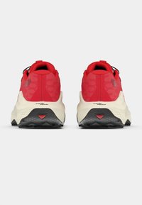 Κόκκινα αθλητικά παπούτσια με υφασμένο επάνω μέρος, μαύρα κορδόνια και σόλες σε κρεμ χρώμα. Διαθέτουν λογότυπο και ελαστική επικάλυψη στο κάτω μέρος για καλύτερη πρόσφυση.