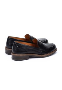 Mocassins en cuir noir avec une finition lisse, présentant des accents cousus, un petit talon et un design matelassé à l'avant sur la tige.