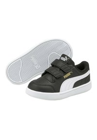 Baskets en noir et blanc avec une tige en cuir synthétique, deux bandes Velcro et une semelle en caoutchouc texturée avec un motif en chevrons.