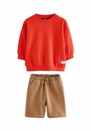 Rød bomulds sweatshirt med sænkede skuldre og ribbede manchetter; tan shorts med elastisk talje og to sidelommer.