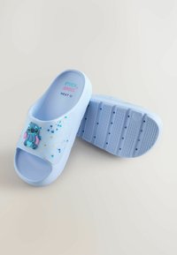 Șlapi cu talpă joasă de culoare albastru deschis, cu un finisaj lucios, având personajul Stitch și accente mici colorate. Textul de pe talpă spune „STITCH ANGEL NEXT 12.”