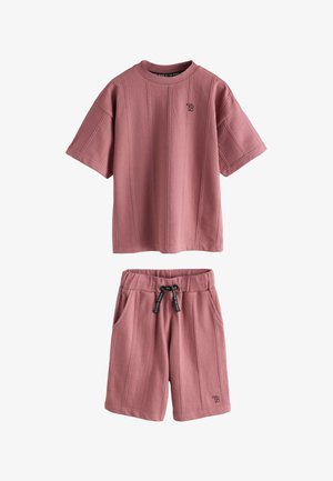 Kortærmet støvet lyserød striktop og matchende shortsæt med sort snor og lille broderet logo på brystet og shorts.
