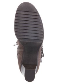 Semelle de botte chelsea en daim marron avec un caoutchouc texturé pour l'adhérence, dotée d'un petit talon empilé et de rainures verticales pour la traction.