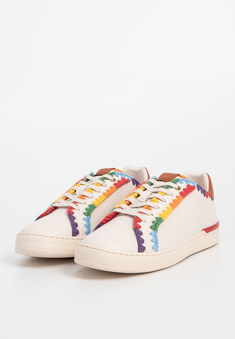 Off-white Sneaker mit regenbogenfarbener geflochtener Kante entlang der Seiten und Schnürsenkel, ausgestattet mit hellbraunen Fersenlaschen und flachen Gummisohlen.