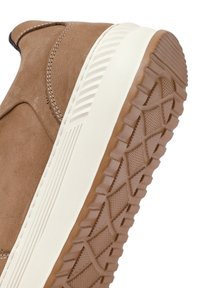 Zapato sin cordones de ante marrón con suela de goma crema, que cuenta con una textura en la suela para mayor agarre y costuras en contraste a lo largo de la parte superior.