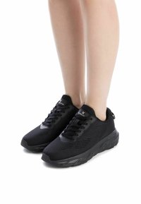 Zapatillas deportivas negras con parte superior de malla, diseño con cordones, cuello acolchado y suela texturizada, que cuentan con una construcción ligera.