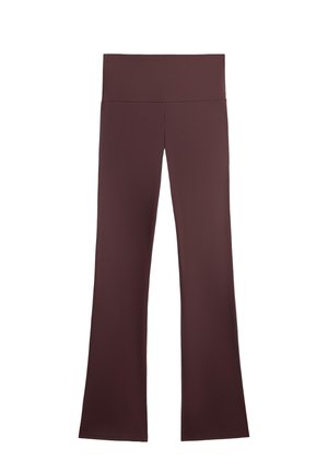 Pantaloni de yoga maron cu un talie lată și înaltă și picioare evazate. Realizați dintr-un material neted și elastic, cu margini curate și fără modele vizibile.