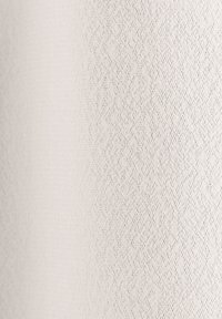 Gros plan sur un tissu texturé beige clair avec un motif subtil de petits points répartis uniformément sur la surface.