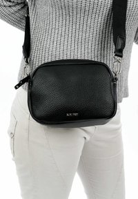 Borsa a tracolla in pelle nera con una texture a granuli, forma rettangolare, tracolla regolabile e finiture in metallo argentato.