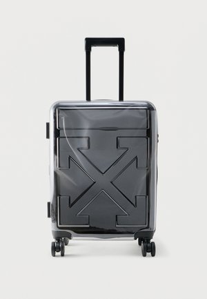 Valise rigide noire avec poignée extensible et quatre roues, dotée d'un motif embossé de flèches croisées sur le devant.