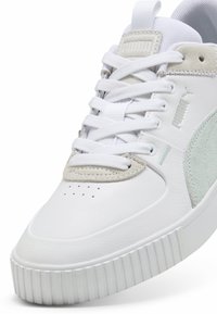 Fehér sneaker bőrből és velúrból készült akcentusokkal, textúrázott oldalsó panellel, gumitalppal és lapos cipőfűzőkkel. Diszkrét logó részlet az oldalon.