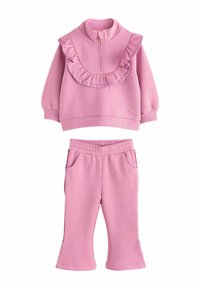 Chándal de forro polar rosa que incluye una sudadera con cremallera con detalles de volantes y unos pantalones ajustados a juego con cintura elástica y bolsillos.