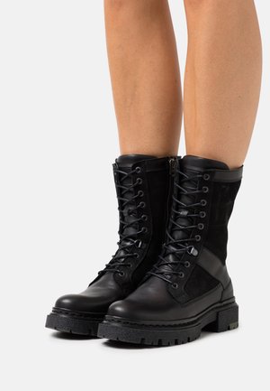 Botas de tobillo de cuero negro y ante con un diseño de cordones, cierre de cremallera, suela de goma texturizada y puntera reforzada.