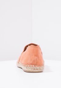 Espadrille en daim orange avec une semelle intermédiaire en jute et une forme arrondie. Dotée d'une texture douce et d'un design ouvert à l'arrière, idéale pour les temps chauds.