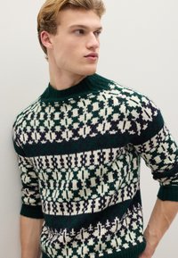 Strickpullover mit einem Muster in Dunkelgrün, Weiß und Marineblau, mit hohem Kragen und elastischen Bündchen, der aufwendige geometrische Designs zeigt.