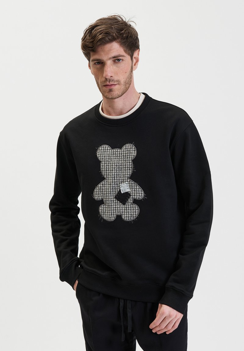 Zwarte sweatshirt met een berenontwerp in een houndstooth-patroon en een stoffen patch. Ronde halslijn en geribde manchetten. Zachte textuur.