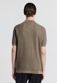 Braunes Poloshirt mit kurzen Ärmeln, das ein strukturiertes Maschenmuster, einen klassischen Kragen und gerippte Bündchen aufweist, gestaltet mit einem geraden Saum.