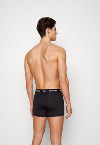 Schwarze Boxershorts mit einer figurbetonten Passform und einem breiten elastischen Bund, der den Markennamen "ONLY&SONS" in weißen Buchstaben trägt.