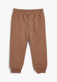 Braune Sweatpants mit elastischem Bund und gekrempeltem Knöchel aus weichem Stoff, flach auf einem weißen Hintergrund präsentiert.