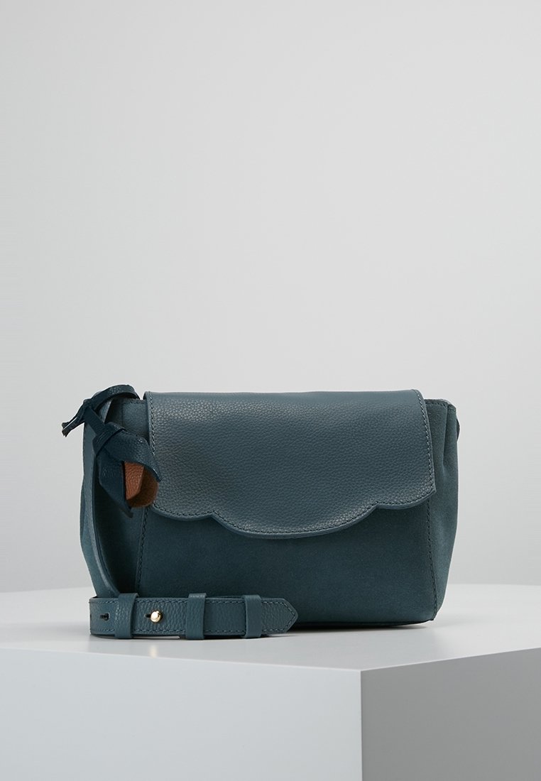 Turkos läderhandväska med en vågig flap, texturerad yta och en avtagbar rem. Inkluderar en sidoknutdetalj och detaljer i guld.