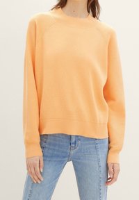 Pomarańczowy prążkowany sweter z okrągłym dekoltem i długimi rękawami, o luźnym kroju i kontrastowej taśmie na dolnym brzegu.