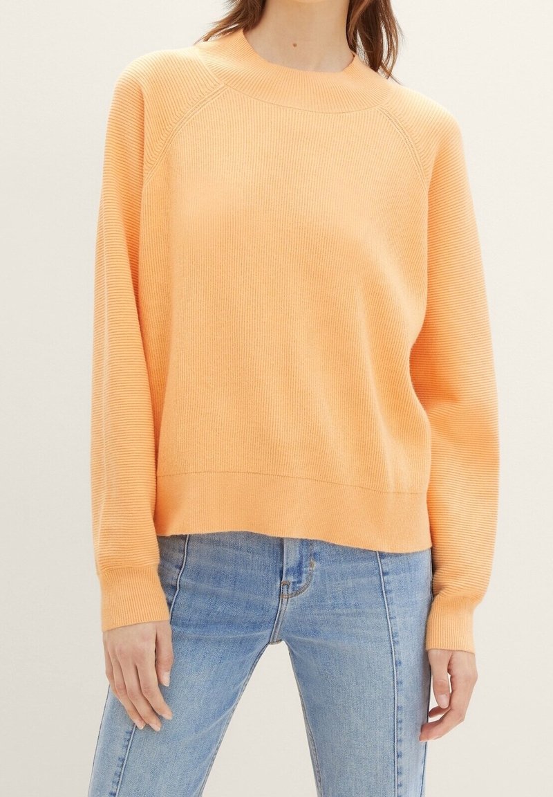 Pomarańczowy prążkowany sweter z okrągłym dekoltem i długimi rękawami, o luźnym kroju i kontrastowej taśmie na dolnym brzegu.