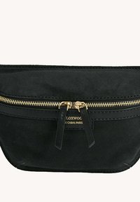 Sac en suede noir avec fermeture éclair dorée, présentant une forme plate, des accents en cuir et un logo subtil gravé à l'avant.